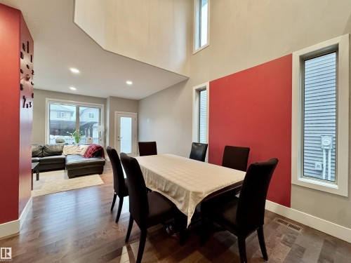 Spacious dining area featuring wood-finish flooring, a double-height ceiling, and large windows providing ample illumination - 3254 Allan Way, Edmonton, AB 