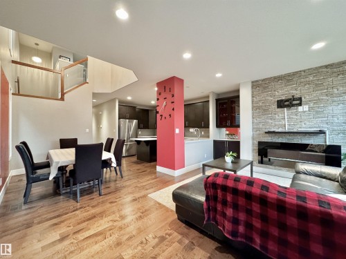 Open-concept living space featuring wood-finish flooring, recessed lighting, and a stone-accented wall - 3254 Allan Way, Edmonton, AB 
