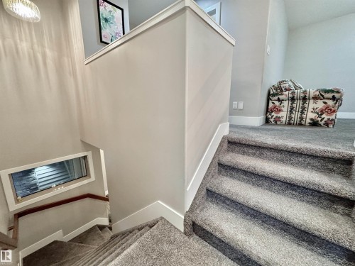 Carpeted staircase featuring white trim, light gray wall paint, and a built-in window with horizontal blinds - 3254 Allan Way, Edmonton, AB 