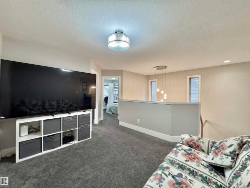 Carpeted upper-level landing featuring a contemporary multi-bulb chandelier and two recessed windows - 3254 Allan Way, Edmonton, AB 
