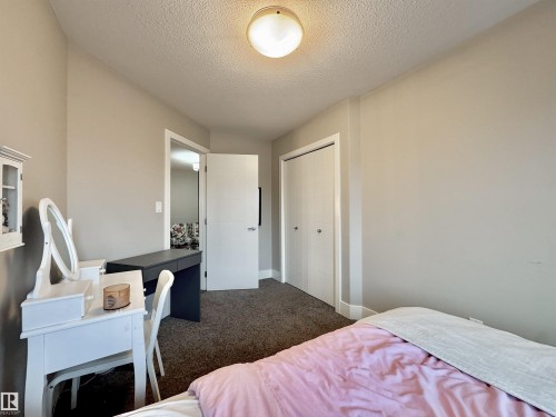 Carpeted room featuring neutral wall tones, a flush-mount ceiling light fixture, a paneled door, and bi-fold closet doors - 3254 Allan Way, Edmonton, AB 