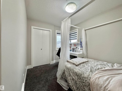 Room featuring neutral wall paint, dark carpet flooring, and a window with horizontal blinds - 3254 Allan Way, Edmonton, AB 