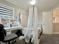 Bedroom featuring a window with horizontal blinds, built-in desk with shelving, gray carpet flooring, and a flush mount ceiling light fixture - 