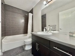 Bathroom featuring a single vanity with dark cabinetry, an integrated sink, and a light-toned countertop - 
