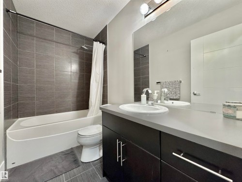 Bathroom featuring a single vanity with dark cabinetry, an integrated sink, and a light-toned countertop - 3254 Allan Way, Edmonton, AB 