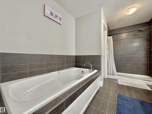 Deep soaking tub with chrome fixtures, surrounded by a tiled deck - 3254 Allan Way, Edmonton, AB 