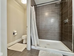 Walk-in shower featuring gray tiled walls, a square rain showerhead, and a white shower pan - 