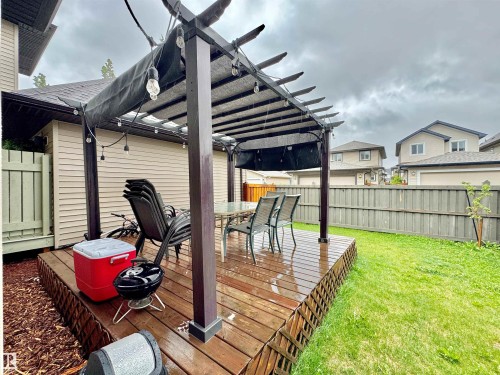 Expansive wooden deck featuring a built-in pergola with a retractable shade canopy and string lighting - 3254 Allan Way, Edmonton, AB 