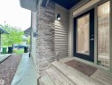 Front entry featuring a full-light door with decorative glass sidelight and transom, stacked stone veneer accent, horizontal siding, and a concrete walkway - 3254 Allan Way, Edmonton, AB 