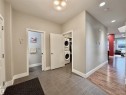 Dedicated laundry area with stacked appliances, featuring ceramic tile flooring and a nearby powder room - 3254 Allan Way, Edmonton, AB 