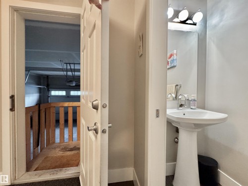 Pedestal sink with chrome faucet, complemented by a rectangular mirror and a three-light vanity fixture - 3254 Allan Way, Edmonton, AB 