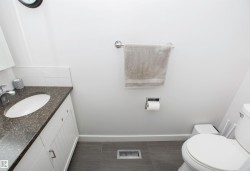 Bathroom featuring a white vanity with panel-front cabinetry, dark speckled countertop, and an undermount sink - 