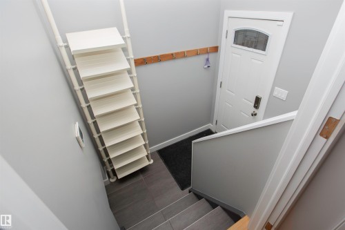 Entryway featuring a white paneled door with an arched glass insert, contemporary digital lock, and a wooden wall-mounted coat rack - 52 Mohawk Crescent, Leduc, AB 