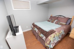 Bedroom featuring light gray walls, white baseboards, and wood-finish flooring - 