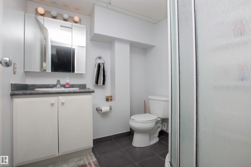 Bathroom featuring a white vanity with a gray countertop, an integrated sink, and a mirrored medicine cabinet - 52 Mohawk Crescent, Leduc, AB 