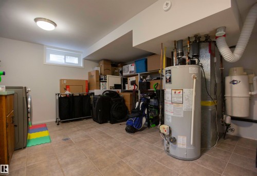 Utility room featuring ceramic tile flooring, a built-in water heater, and a central vacuum system - 52 Mohawk Crescent, Leduc, AB 