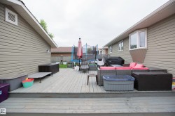 Expansive wood-finish deck with multiple levels, featuring a bay window on the residence and horizontal siding - 