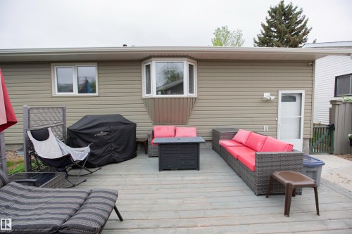 Expansive wood-finish deck with a bay window and a screen door entry, featuring horizontal siding - 52 Mohawk Crescent, Leduc, AB 