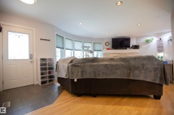 Open living area featuring hardwood flooring, recessed lighting, and a bay window with blinds - 
