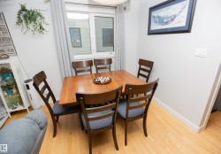 Dining area featuring wood-finish flooring, a contemporary ceiling light fixture, and a window with light-filtering curtains - 