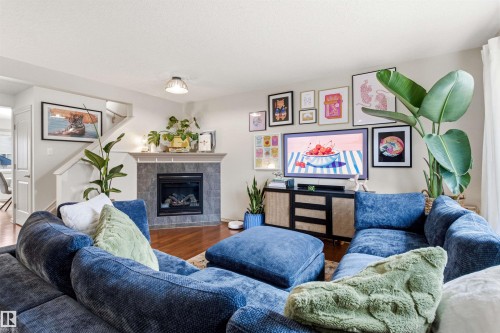 Living area featuring wood-finish flooring, a tiled fireplace with mantel, and a built-in entertainment console - 14807 141 Street, Edmonton, AB 
