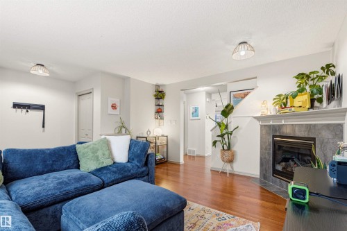 Living area featuring wood-finish flooring, a fireplace with a stone surround and mantel, and recessed lighting - 14807 141 Street, Edmonton, AB 