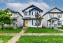 Two-story residence featuring light blue siding with dark blue trim, a prominent yellow front door, and a concrete walkway leading to the entrance - 14807 141 Street, Edmonton, AB 