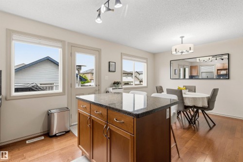Kitchen island with wood cabinetry and dark stone countertop - 14807 141 Street, Edmonton, AB 