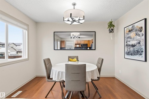Bright dining area featuring wood-finish flooring and a contemporary drum pendant light fixture - 14807 141 Street, Edmonton, AB 