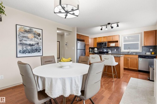 Open-concept dining area featuring wood-finish flooring, a contemporary chandelier, and recessed lighting - 14807 141 Street, Edmonton, AB 