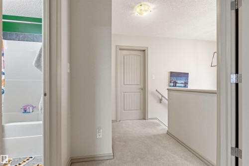 Upper-level hallway featuring light carpeting, neutral wall paint, and white trim - 14807 141 Street, Edmonton, AB 