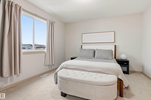 Bright bedroom with a large window, neutral carpeting, and light-colored walls - 14807 141 Street, Edmonton, AB 