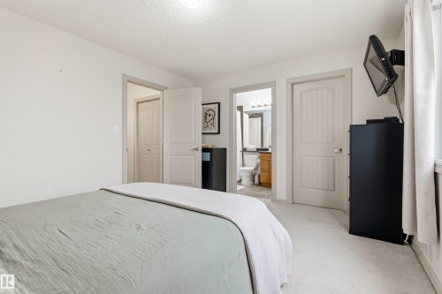 Light-toned carpeting throughout the space, featuring a panel-style door, an additional closet with bi-fold doors, and a bathroom entry with a vanity and mirror - 14807 141 Street, Edmonton, AB 