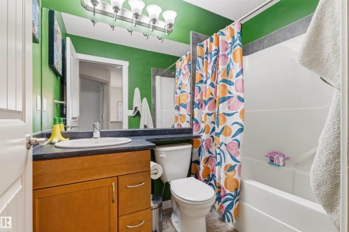 Bathroom featuring a wood-finish vanity with an integrated sink, a dark countertop, and a built-in mirror - 14807 141 Street, Edmonton, AB 