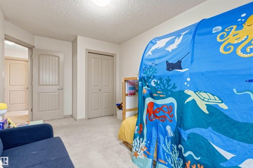 Carpeted room featuring a white ceiling, painted walls, and light-toned interior doors - 14807 141 Street, Edmonton, AB 