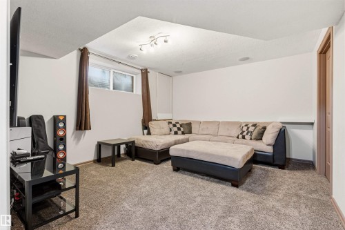 Carpeted recreation room featuring an egress window, built-in ceiling speakers, recessed lighting, and a neutral color palette - 14807 141 Street, Edmonton, AB 
