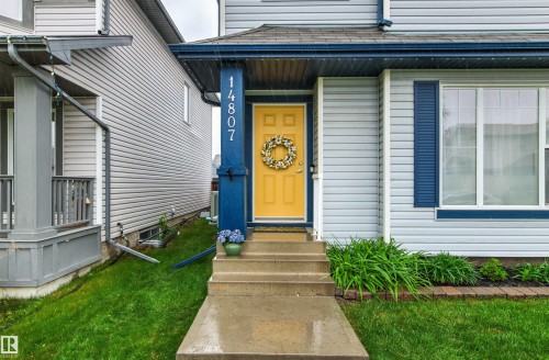 Exterior facade featuring light gray siding, a bright yellow entry door, and dark blue accents - 14807 141 Street, Edmonton, AB 