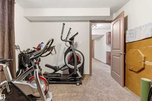 Carpeted room with white walls, a brown door with vertical panels, and a brown door frame - 14807 141 Street, Edmonton, AB 