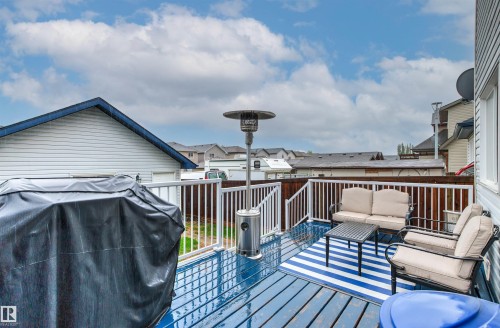 Outdoor deck featuring blue-painted wood-finish flooring, white spindle railings, and a privacy fence - 14807 141 Street, Edmonton, AB 