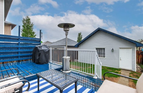 Blue-painted wood deck featuring a horizontal slat privacy fence and white railing - 14807 141 Street, Edmonton, AB 