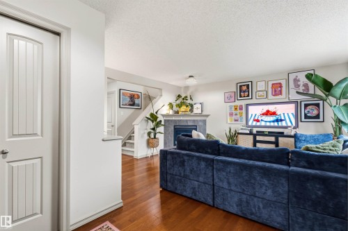 Living room featuring wood-finish flooring and a fireplace with a stone surround and mantle - 14807 141 Street, Edmonton, AB 