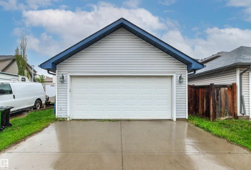 Attached garage featuring a panel-style door, blue roof trim, and two exterior sconces - 14807 141 Street, Edmonton, AB 