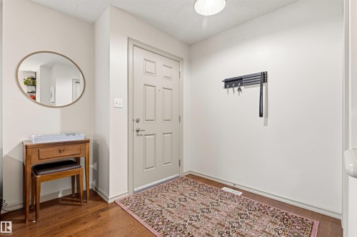 Entryway featuring a paneled door, wood-finish flooring, and white walls - 14807 141 Street, Edmonton, AB 