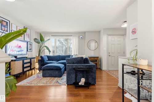 Spacious living area featuring wood-finish flooring, ample natural light, and a built-in media console - 14807 141 Street, Edmonton, AB 
