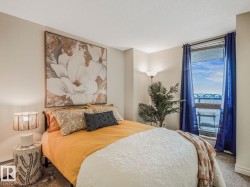 Carpeted bedroom featuring a large window with blue drapery, a floor lamp, and a modern wall art piece - 