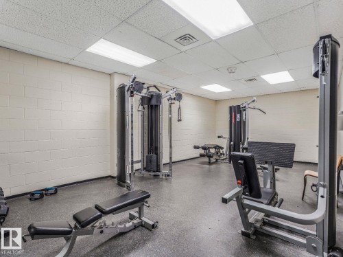 Dedicated fitness area featuring durable rubber flooring, multiple strength training machines, and ample overhead lighting - 806 10149 Saskatchewan Drive, Edmonton, AB 