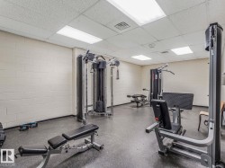 Dedicated fitness area featuring durable rubber flooring, multiple strength training machines, and ample overhead lighting - 