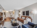 Open concept living area featuring wood-finish flooring, light grey wall paint, and a textured area rug - 806 10149 Saskatchewan Drive, Edmonton, AB 