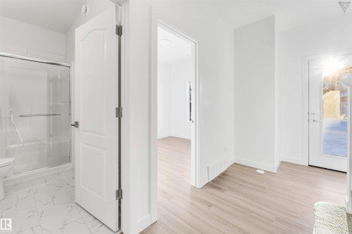 White-paneled interior door opening to a light-filled space with wood-finish flooring - 1224 14 Avenue Nw, Edmonton, AB - Indoor Photo Showing Other Room