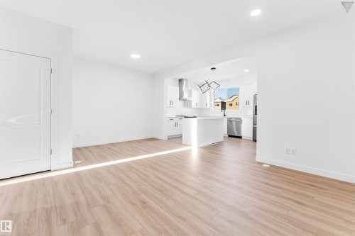 Open-concept living area featuring wood-finish flooring, recessed lighting, and a white paneled door - 1224 14 Avenue Nw, Edmonton, AB - Indoor